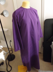 A purple robe hanging on a dress form.