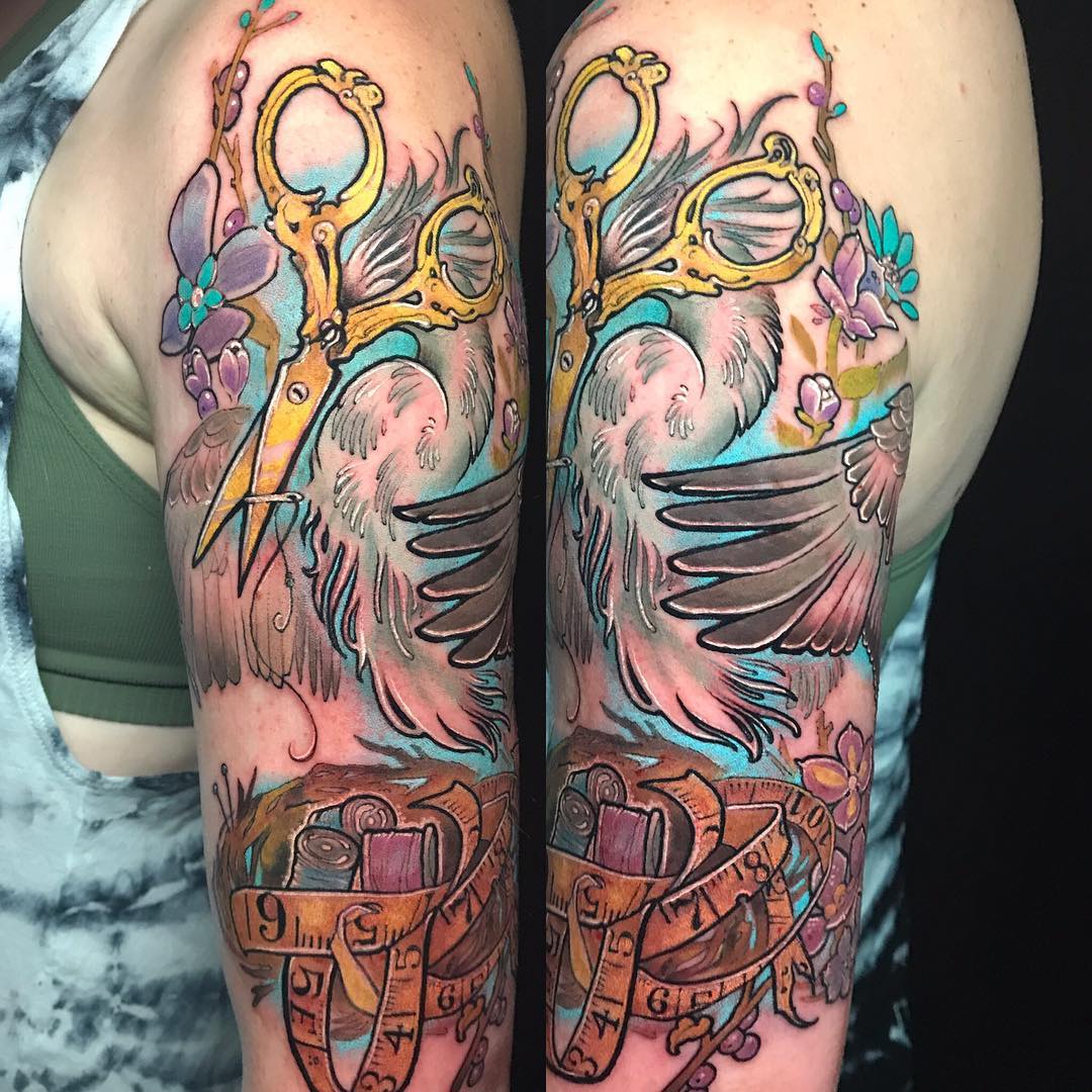 Brightly colored half sleeve tattoo of a stork with scissors for a head over a nest of thread spools.