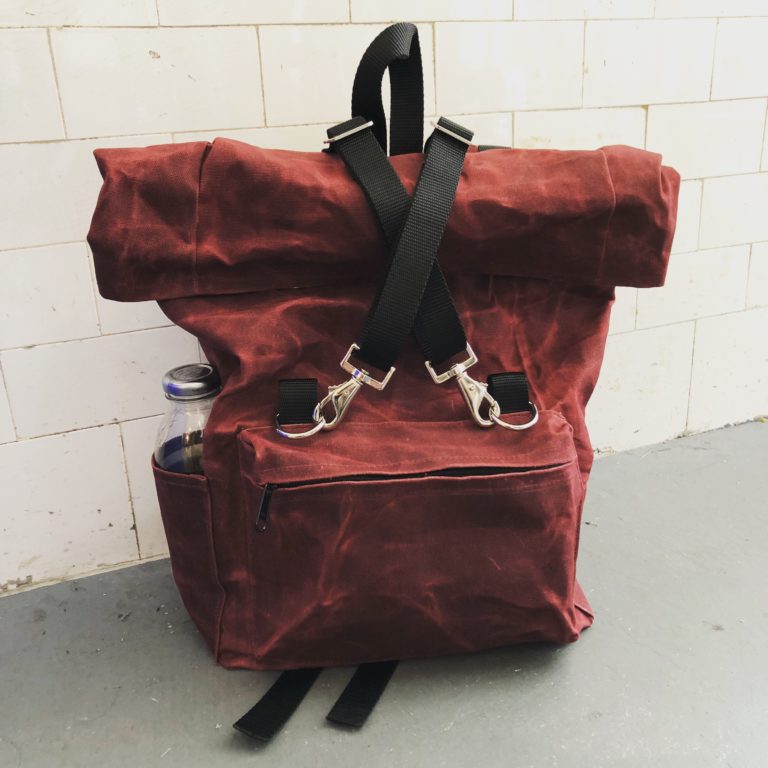 Burgundy waxed canvas roll-top backpack.