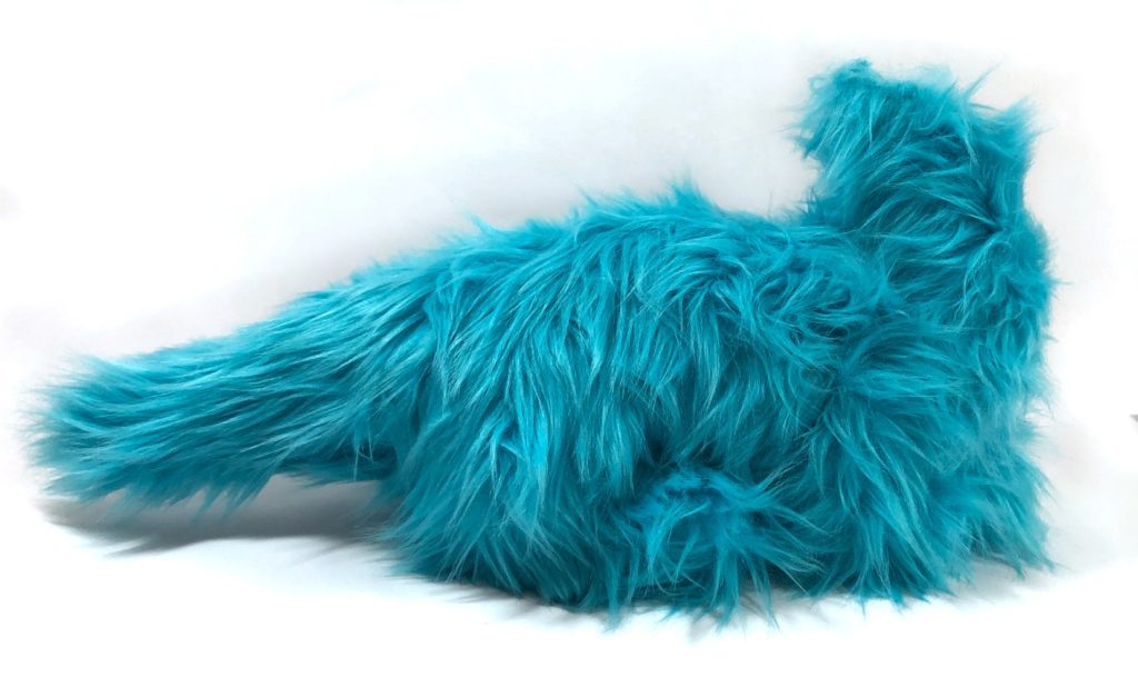 Photo of an unfinished dragon plush with long, shaggy fur. Front legs are not visible, and the back legs are barely visible. It does not yet have a head.