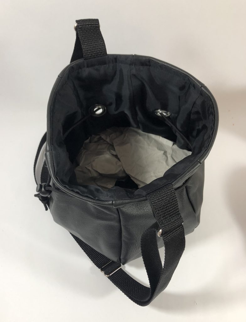 Top view of black leather drawstring bag. It is lined with satin-like black fabric.