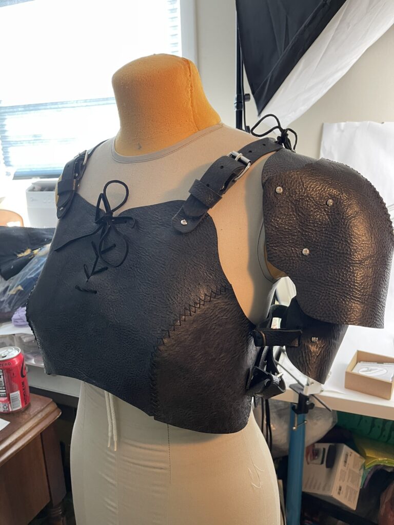 A photo of a fashion mannequin wearing a black leather demicuirass and one left pauldron. The form is facing slightly left to better show the shoulder armor.